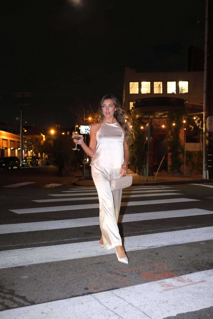 Woman in a white outfit crossing a street at night.