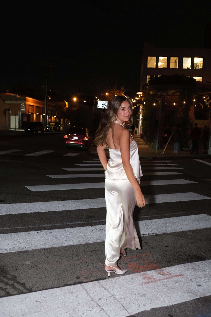 Woman in a white dress standing on a crosswalk at night.