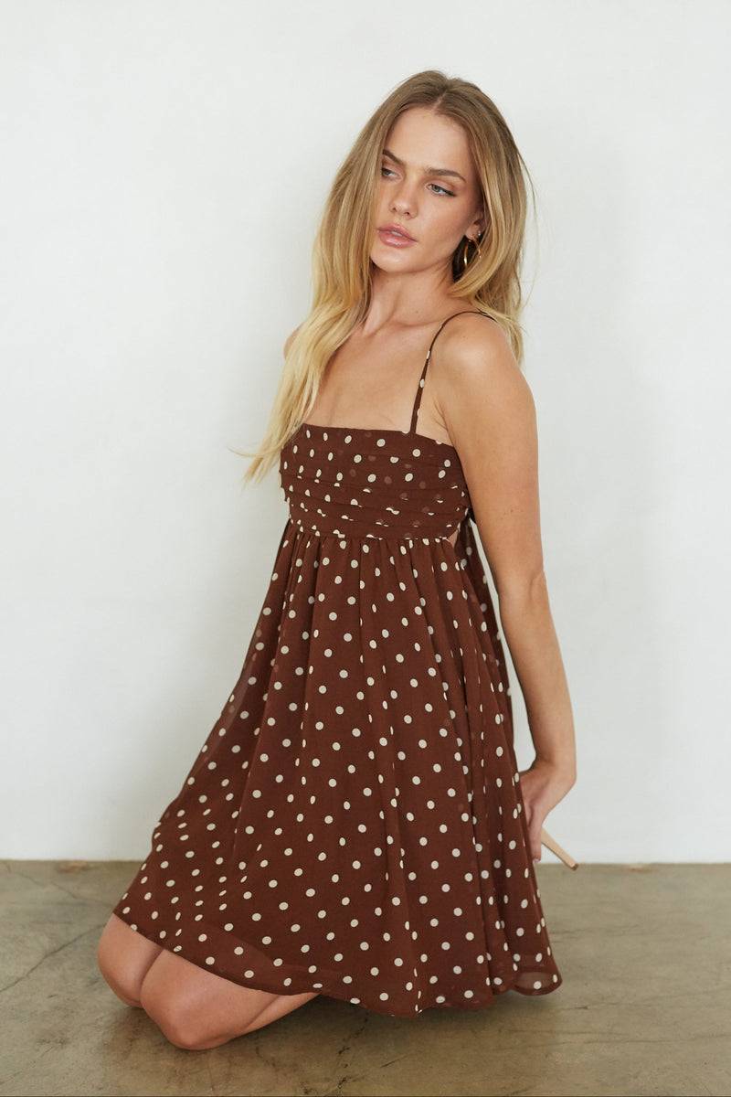 Woman wearing a brown polka dot dress against a white background