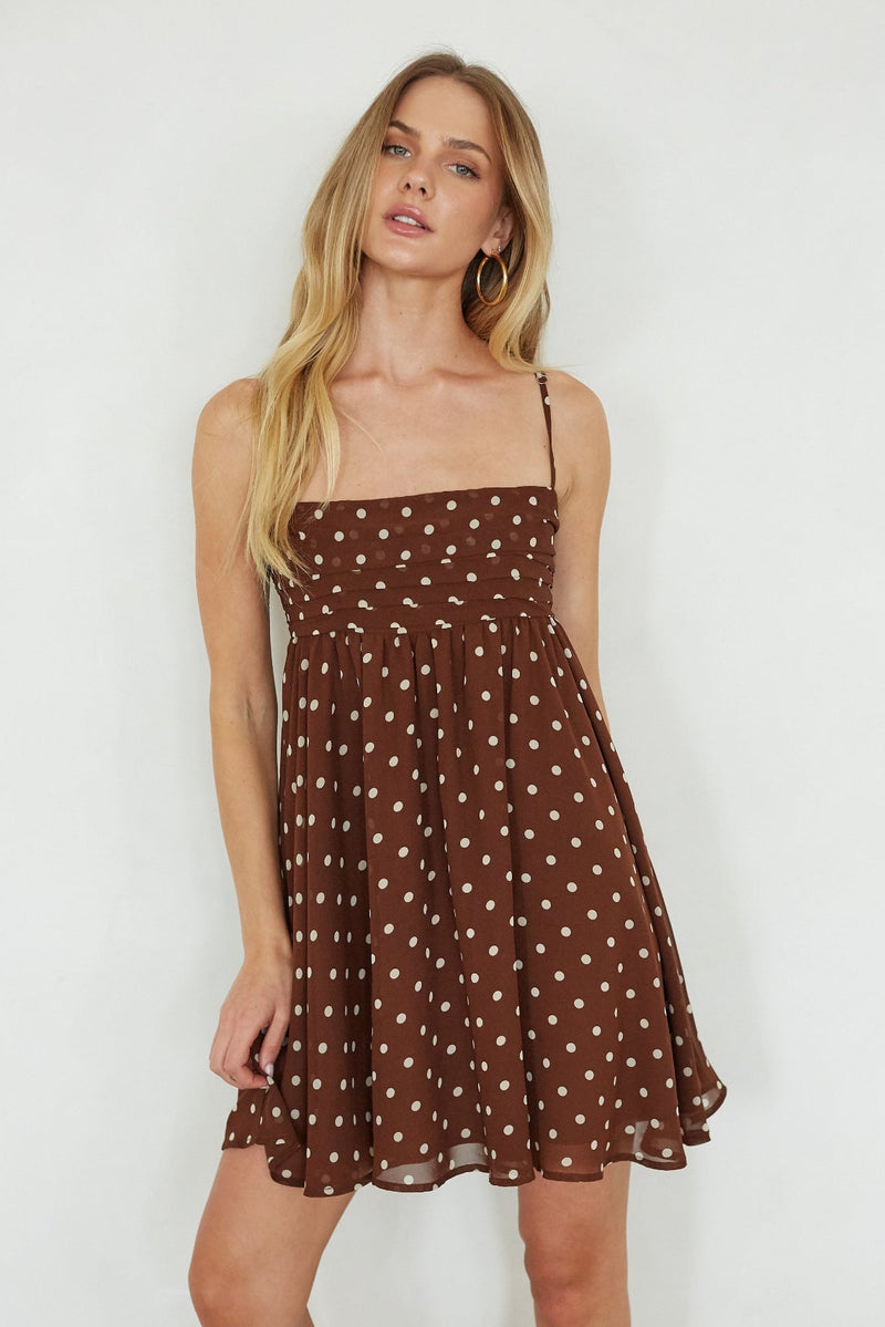 brown-image | Woman wearing a brown polka dot dress against a white background