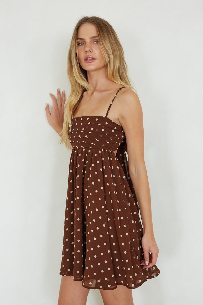 Woman wearing a brown polka dot dress against a white background