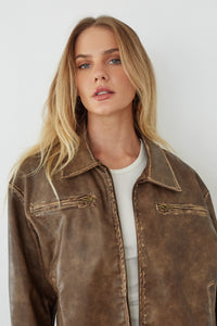 Woman wearing a brown leather jacket against a white background