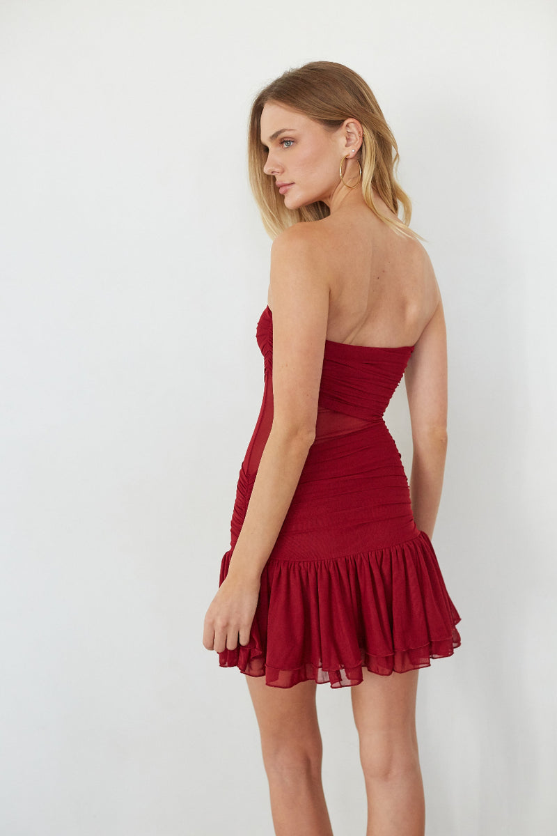 Woman wearing a red strapless dress against a white background