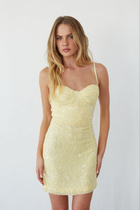 Woman wearing a yellow lace dress against a white background