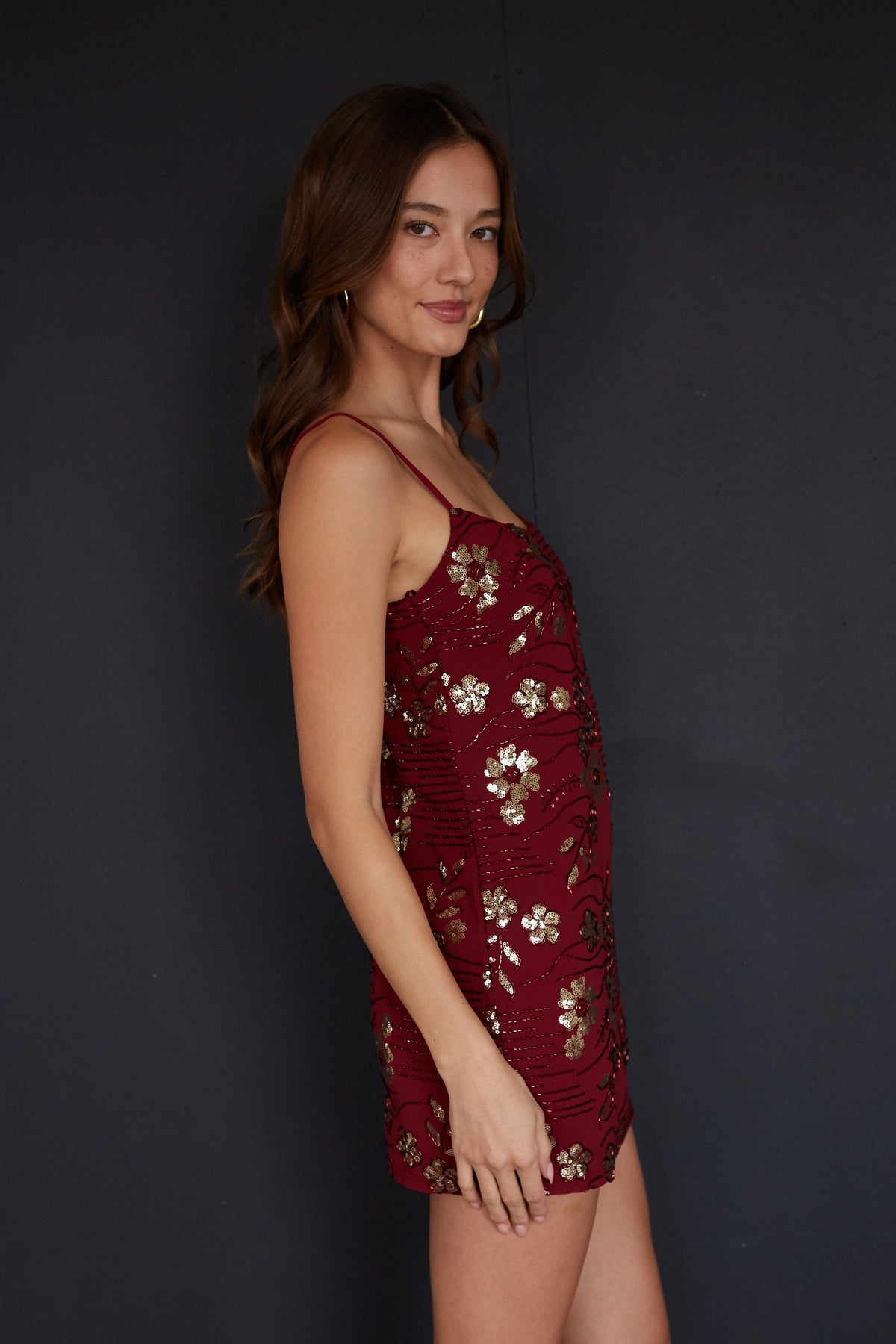 Woman wearing a burgundy dress with floral patterns against a black background