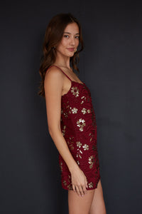 Woman wearing a burgundy dress with floral patterns against a black background