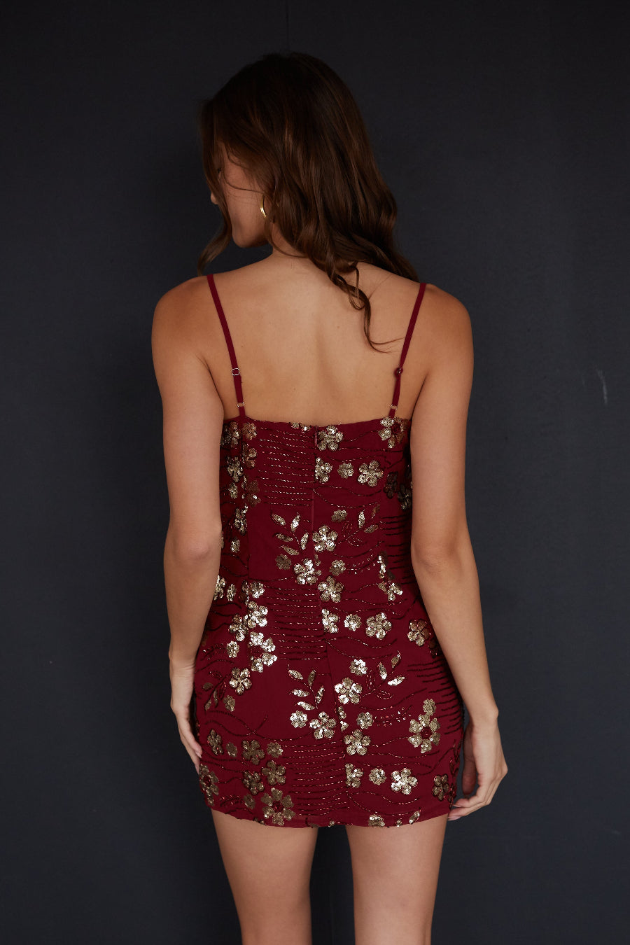 Woman wearing a burgundy dress with floral patterns against a black background