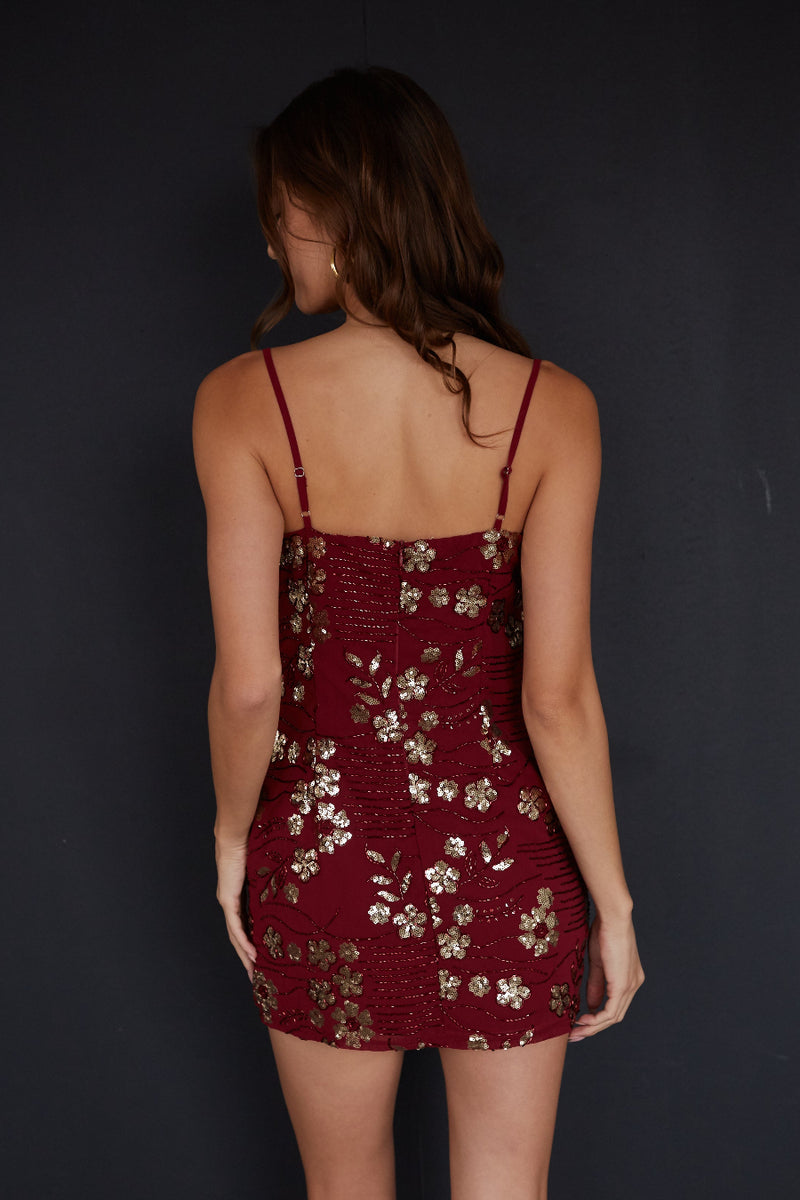 Woman wearing a burgundy dress with floral patterns against a black background
