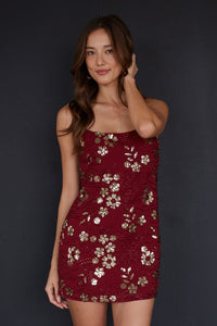 Woman wearing a red floral dress against a black background