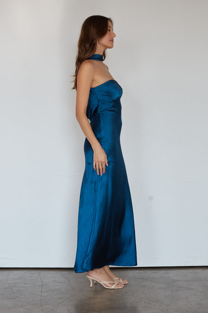 Woman wearing a blue strapless gown against a white background
