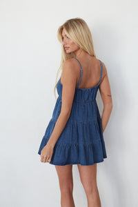 Woman wearing a blue denim dress against a white background