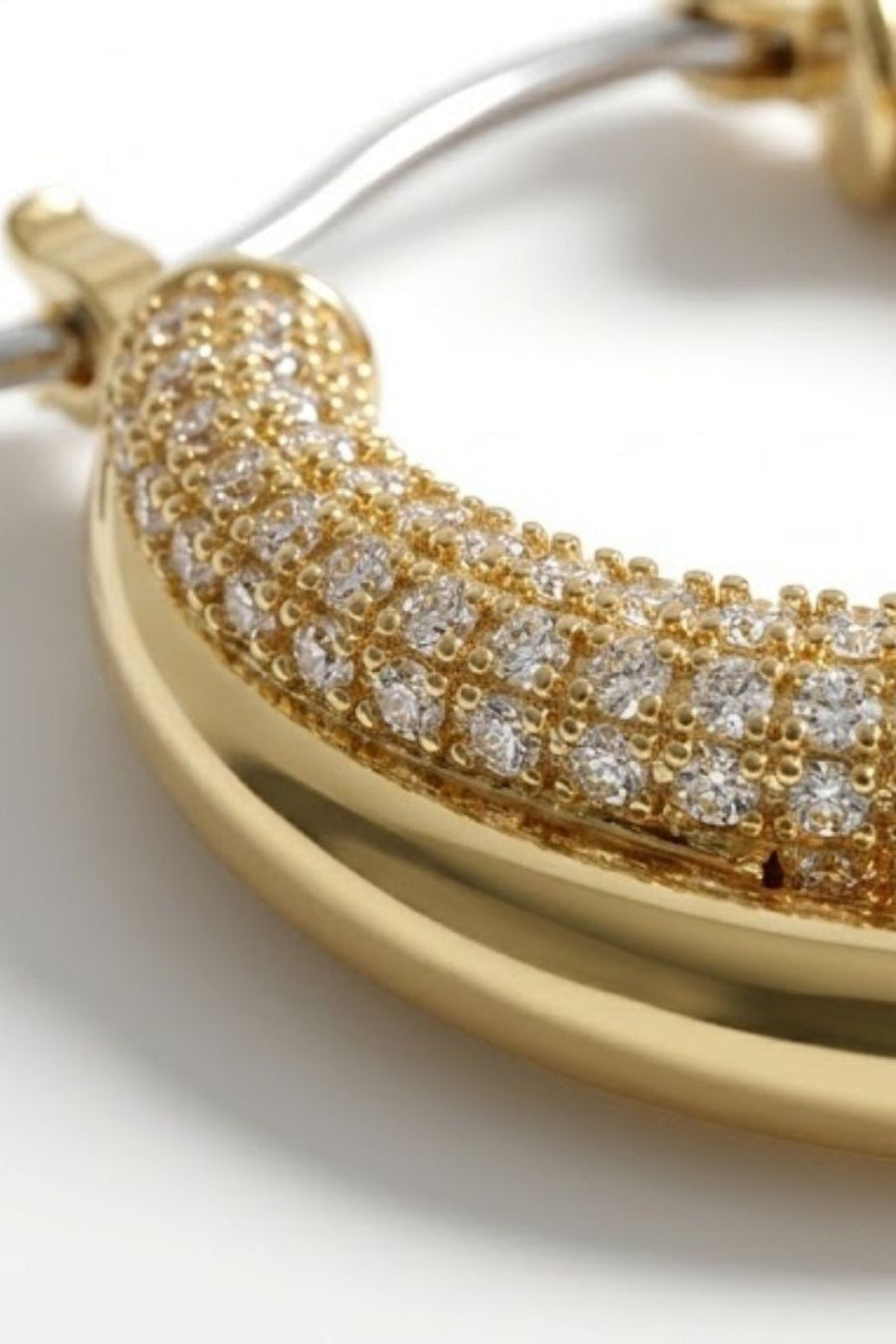 Gold-toned double-hoop earring with a curved front hoop paved with clear stones, shown in a close-up studio shot on a white background.