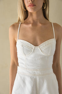 Woman wearing a white dress with thin straps against a beige background