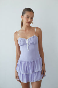 Woman wearing a light purple nightgown against a plain background