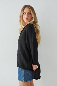 Woman wearing a black sweater and denim skirt on a plain background