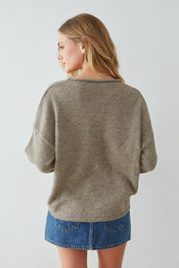 Woman wearing a beige sweater and denim skirt on a plain background