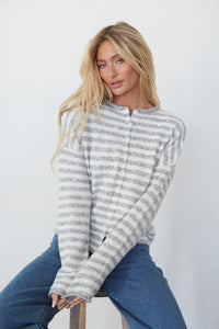 Woman wearing a striped hoodie and jeans against a white background