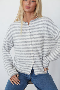 Woman wearing a striped sweater and jeans against a plain background