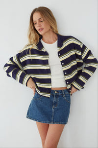 Woman wearing a striped jacket, white shirt, and denim skirt against a white background