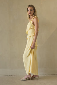 Woman wearing a yellow outfit standing against a beige wall.