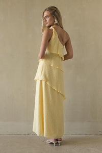 Woman wearing a yellow dress against a beige wall