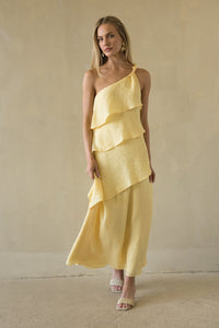 Woman wearing a yellow one-shoulder dress against a plain background