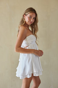 Woman wearing a white strapless dress against a beige background