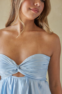Woman wearing a light blue strapless dress with a knot detail.