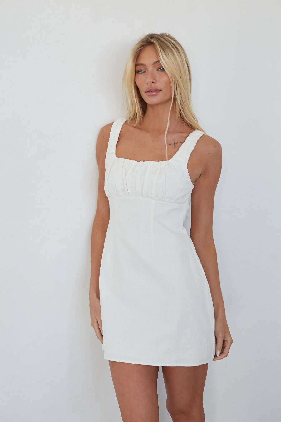 Woman wearing a white dress against a plain background