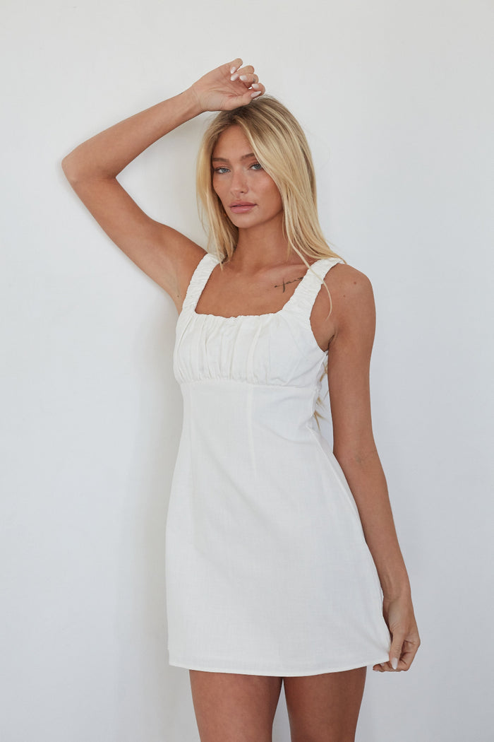 Woman wearing a white dress against a plain background