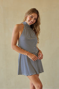 Woman wearing a blue and white striped dress against a beige wall