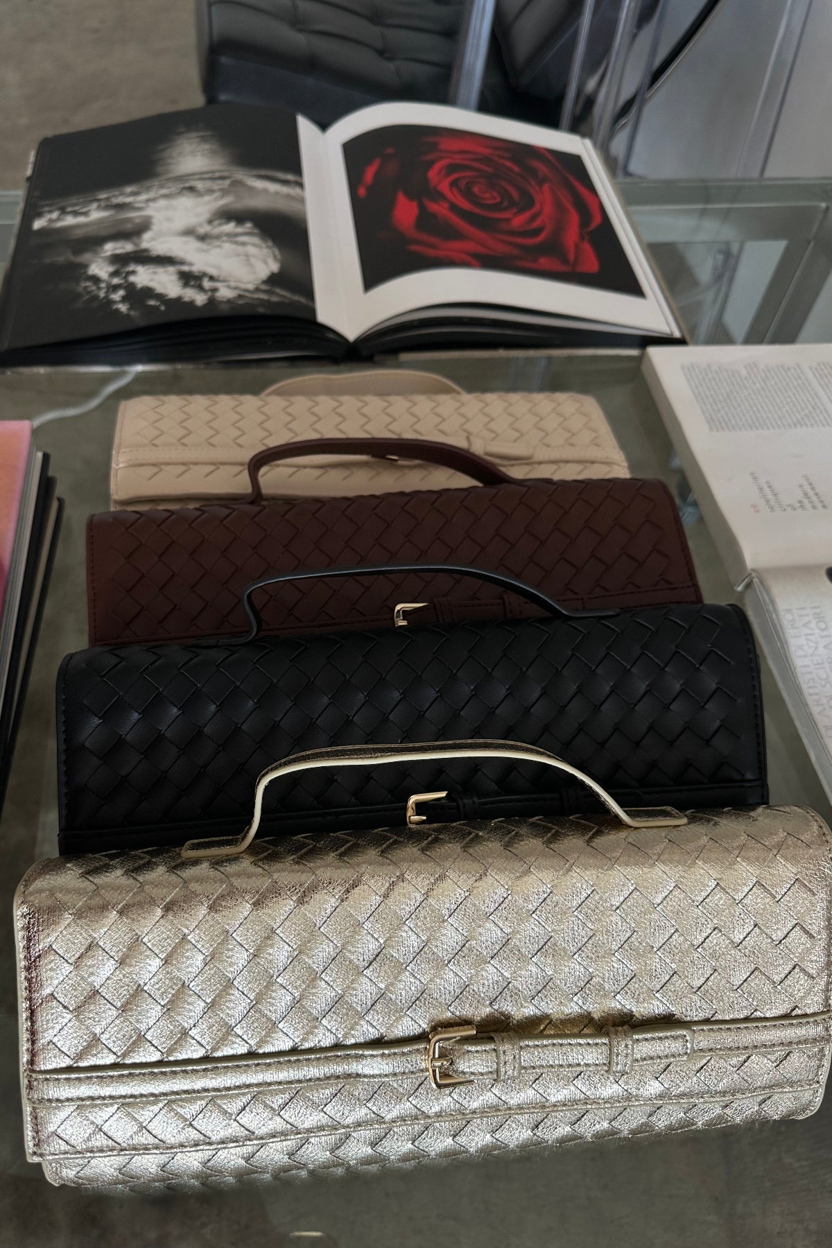 Collection of handbags on a glass surface with books in the background
