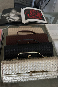 Collection of handbags on a glass surface with books in the background