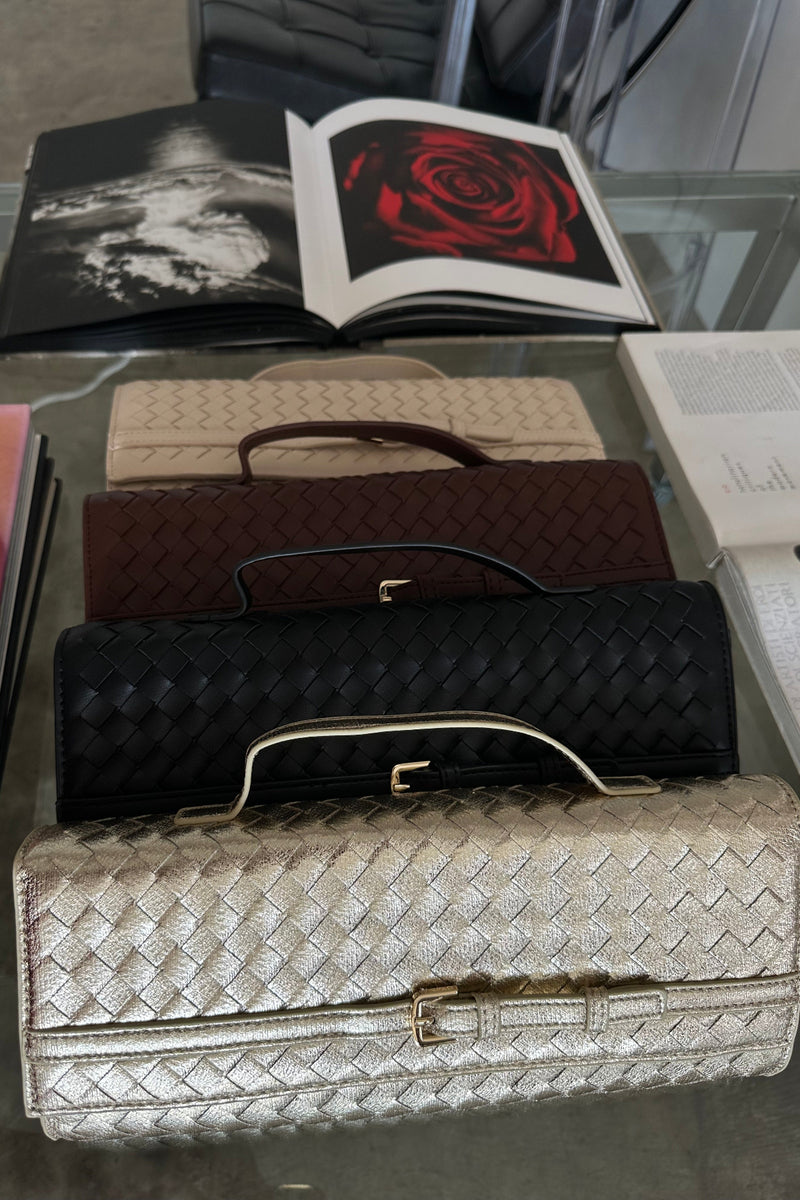 Collection of handbags on a glass surface with books in the background