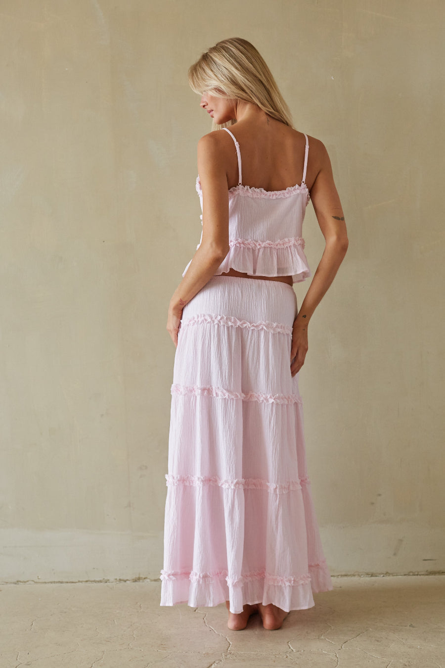 Woman wearing a pink tiered dress against a plain background