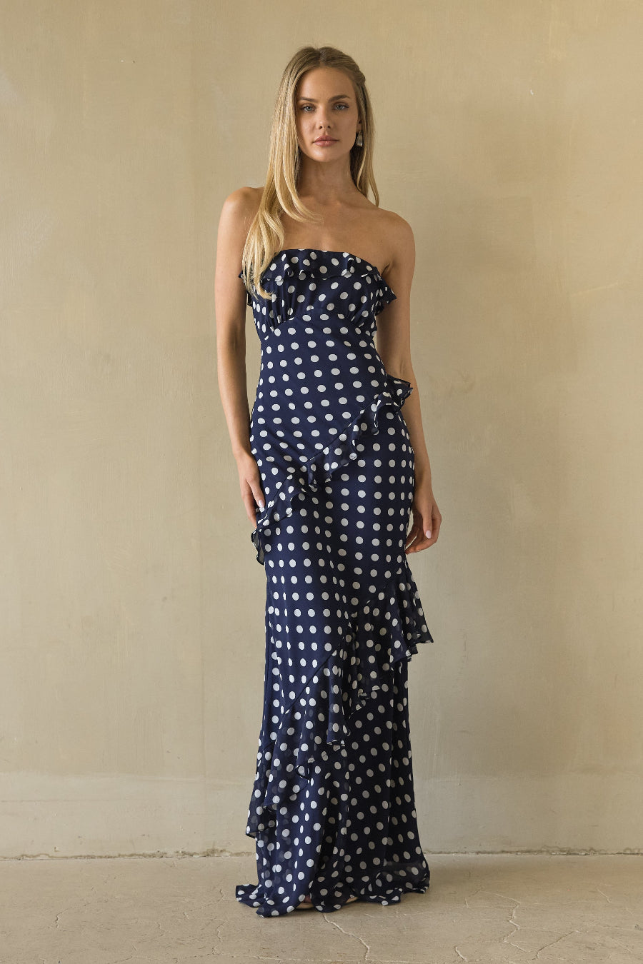 blue-image | Woman wearing a strapless polka dot dress against a beige background