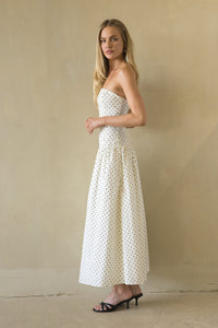 Woman wearing a strapless polka dot dress against a beige background