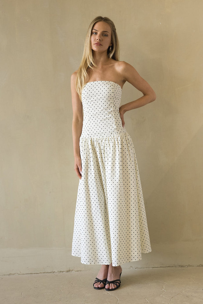 white-image | Woman wearing a strapless polka dot dress against a plain wall.