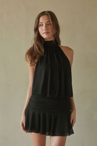 black-image | Woman wearing a black halter neck dress against a beige background