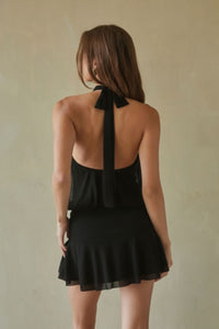 black-image | Woman wearing a black halter neck dress with a plain background
