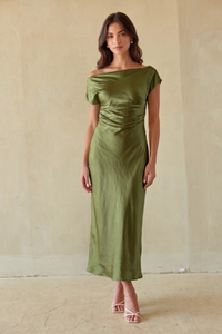 green-image | brunette model wearing an off the shoulder green dress against a beige wall.
