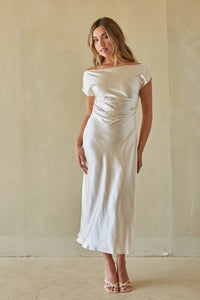 Woman wearing a white off-shoulder dress against a plain background