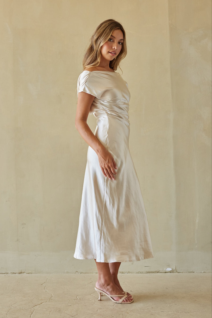 Woman wearing a white dress against a beige wall