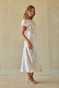 Woman wearing a white dress against a beige wall