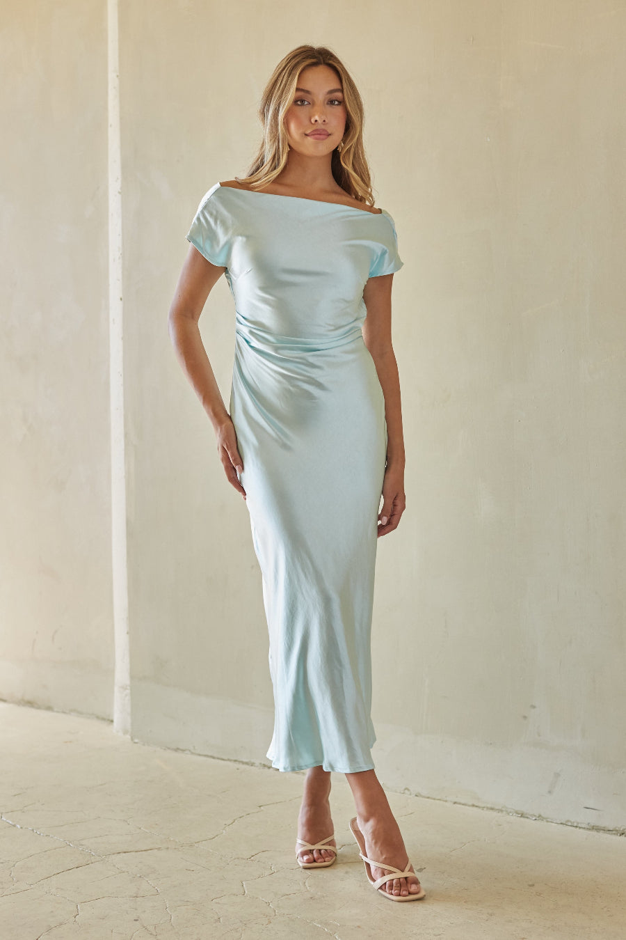 Woman wearing a light blue off-shoulder dress against a plain background