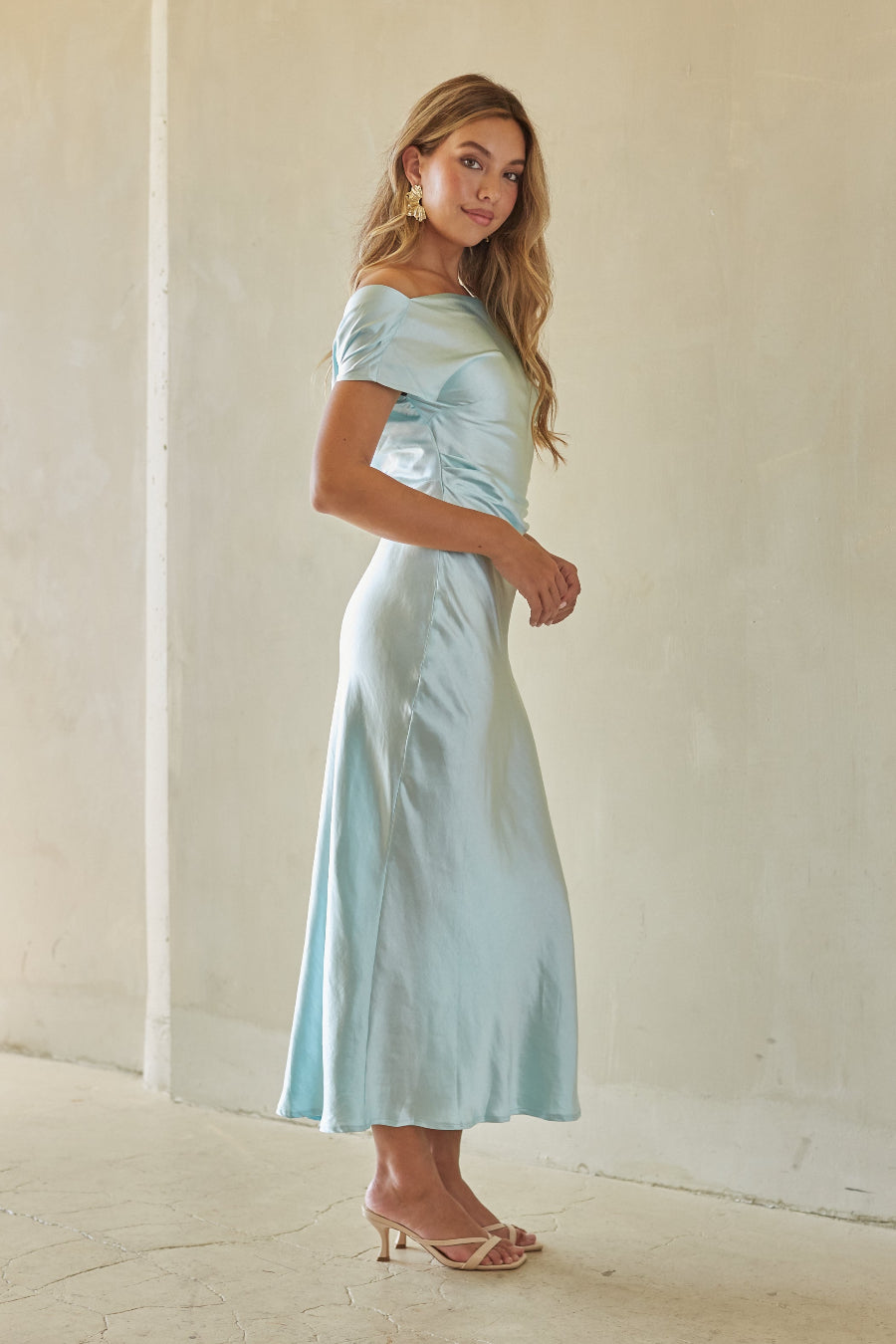 Woman wearing a light blue satin dress against a plain background