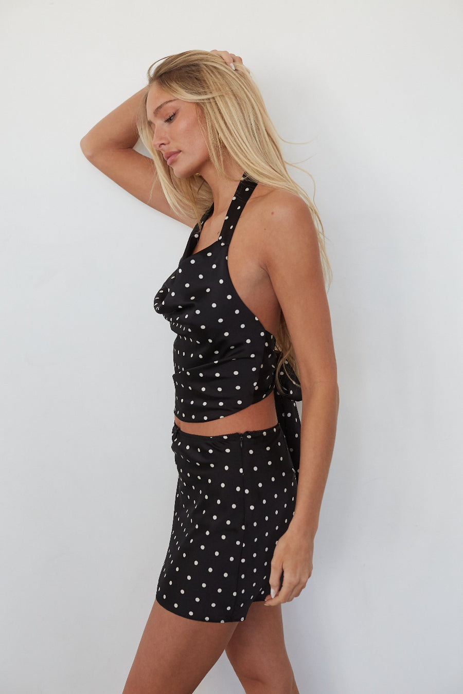 Woman wearing a black polka dot outfit against a white background