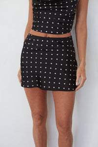 Person wearing a black polka dot skirt on a white background