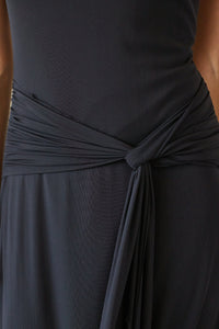 Close-up of a dark black gray wrap dress with a twisted waist sash detail, showing the draped fabric texture.