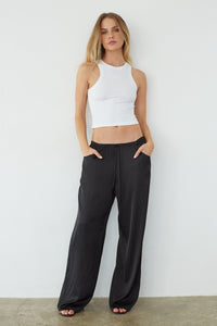 black-image | front-image | Woman wearing a white tank top and black wide-leg pants against a plain background